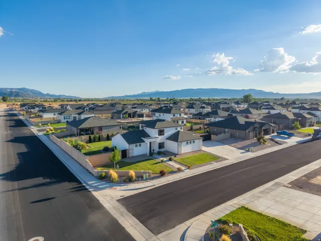 Newly constructed residential neighborhood with paved streets and sidewalks, featuring contemporary homes with landscaped front yards and a distant mountain backdrop