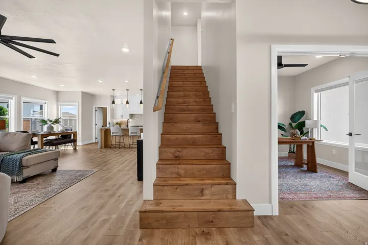 Hardwood stairs with metal railing, wood-finish flooring, recessed lighting, and a room with French doors