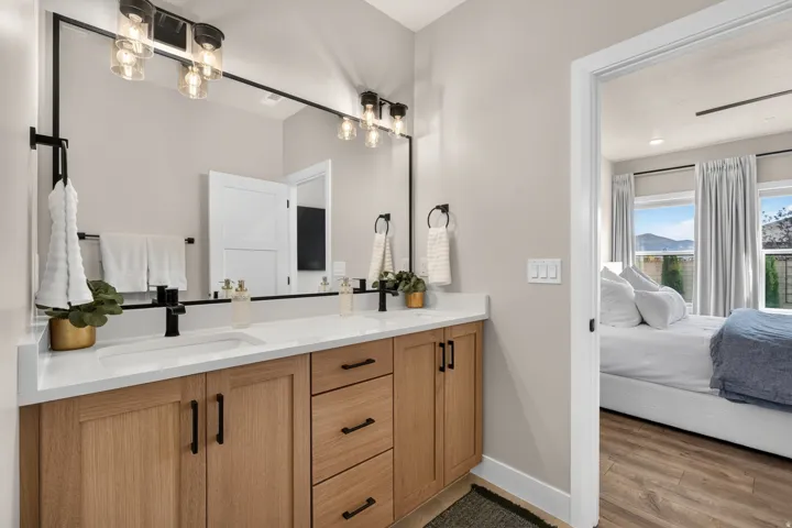 Dual vanity with light wood-finish cabinetry, white countertops, and matte black fixtures
