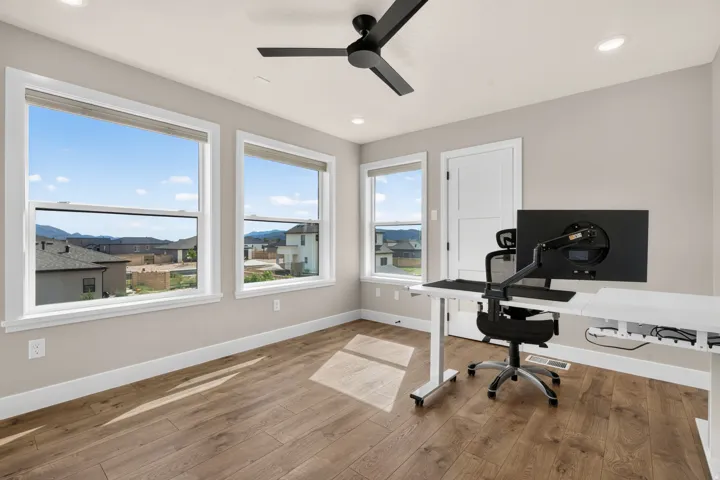 Wood-finish flooring with multiple windows, recessed lighting, and a modern ceiling fan
