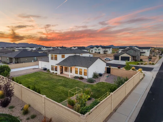 Expansive fenced backyard with a manicured lawn, gravel landscaping, and established plantings