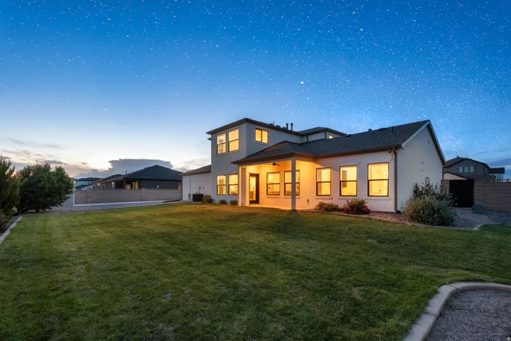 Expansive lawn with a covered patio, stucco exterior, and multi-pane windows