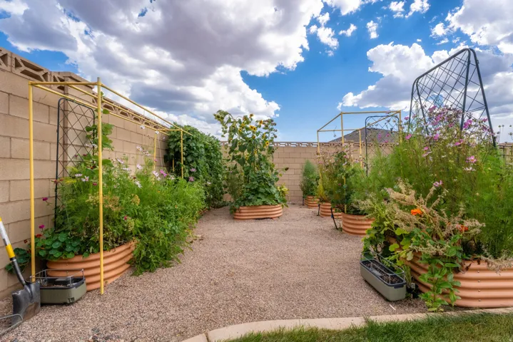 Landscaped backyard featuring raised garden beds, gravel ground cover, and a block perimeter wall