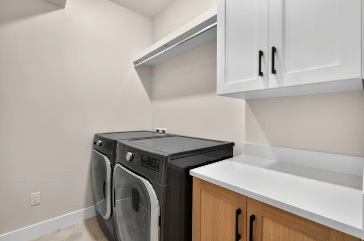 White upper cabinetry with black pulls, light wood-finish lower cabinetry, white countertop, and built-in shelving