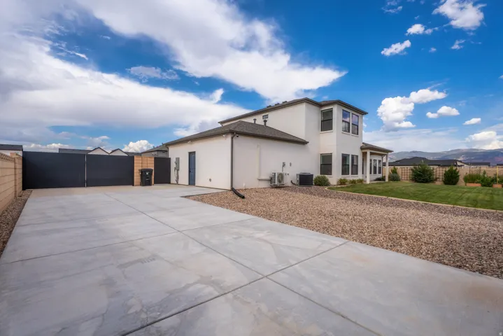 Spacious concrete driveway with a block wall perimeter and dark-toned privacy gates