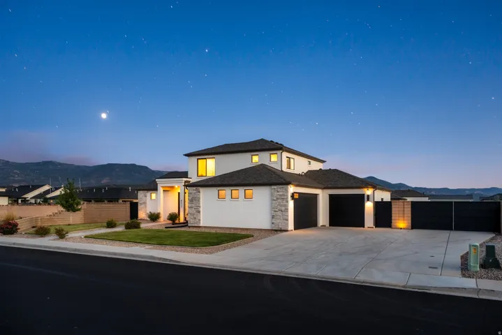 Contemporary exterior with white stucco, stone veneer accents, and a dark shingle roof