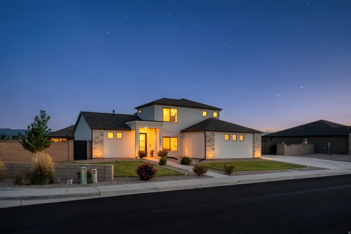 Two-story residence featuring a stucco and stone veneer exterior, a dark shingle roof, and an attached two-car garage