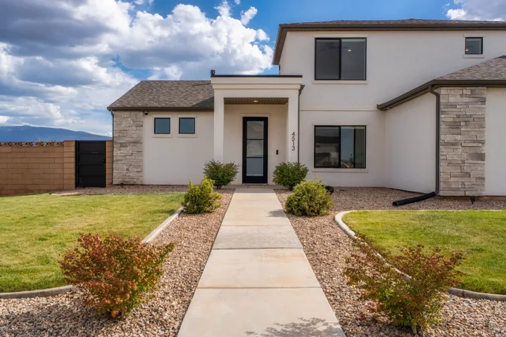 Contemporary stucco exterior with stone accents, a covered entry, and black-framed windows