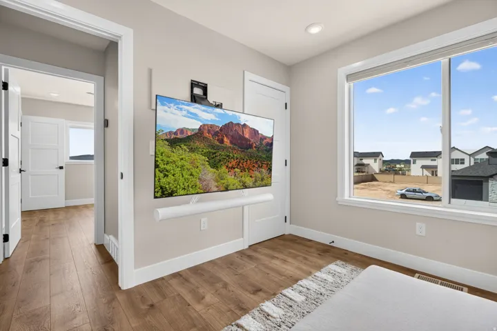 Wood-finish flooring, white trim, recessed lighting, and a large window