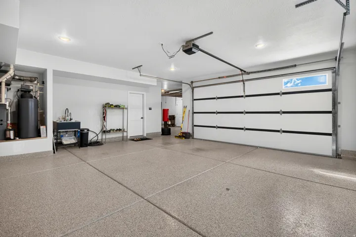 Expansive garage featuring a speckled epoxy floor, recessed lighting, a utility sink, and a white paneled garage door with upper window