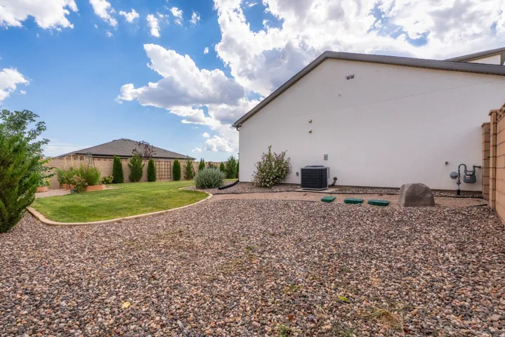 Expansive backyard featuring a manicured lawn, established landscaping, and a privacy fence