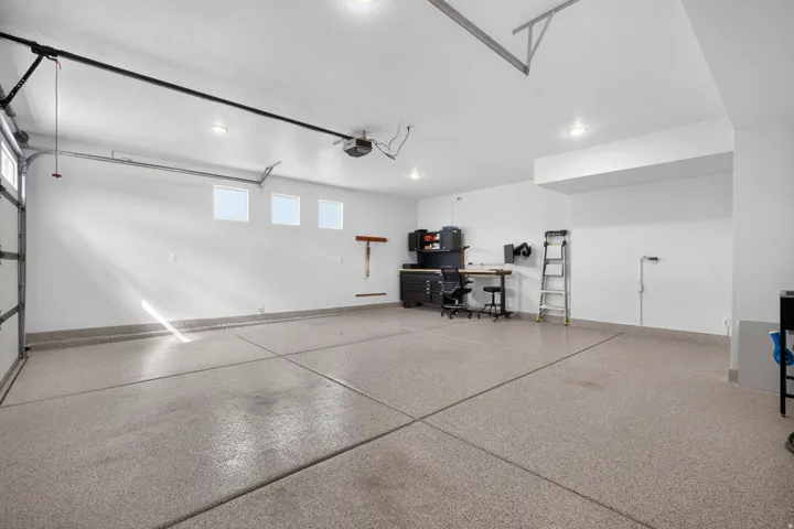 Spacious garage featuring a finished floor coating, multiple windows, recessed lighting, and an automated garage door