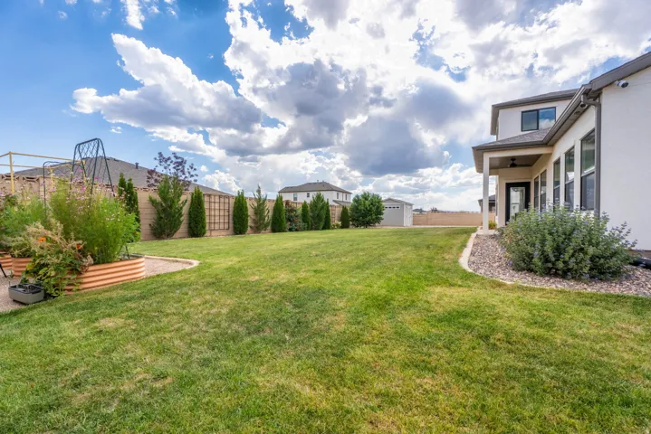 Expansive backyard featuring a manicured lawn, established landscaping, and raised garden beds