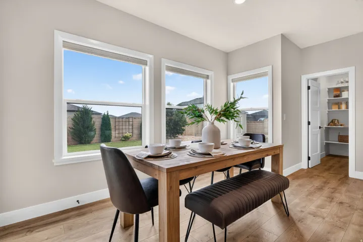 Three large windows with white trim, wood-finish flooring, recessed lighting, and a pantry with built-in shelving