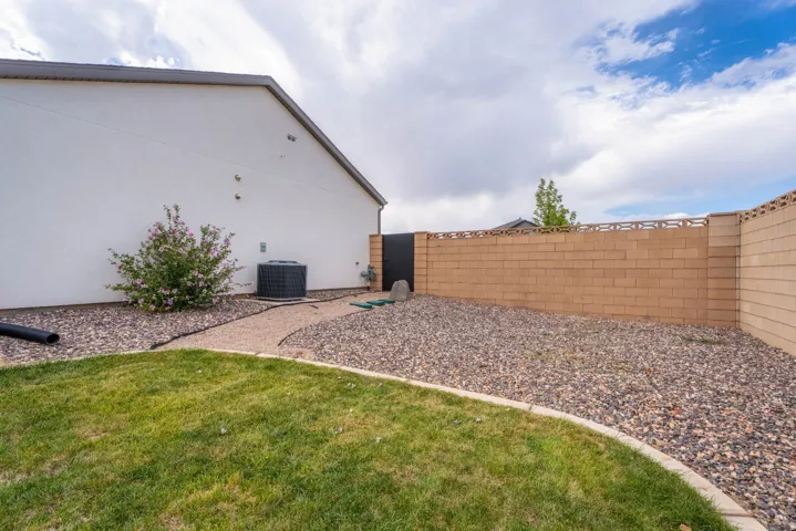 Manicured lawn area with a gravel border, a full height privacy wall, and a side access gate
