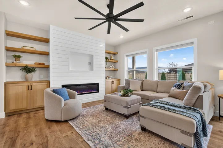 Wood-finish flooring, built-in shelving, white shiplap fireplace surround, linear electric fireplace, and recessed lighting