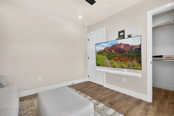 Wood-finish flooring with white trim, recessed ceiling lighting, and a white paneled door