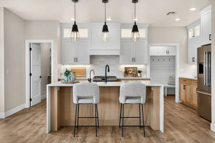Island with a stone countertop, wood-finish flooring, white cabinetry, integrated range, and pendant lighting