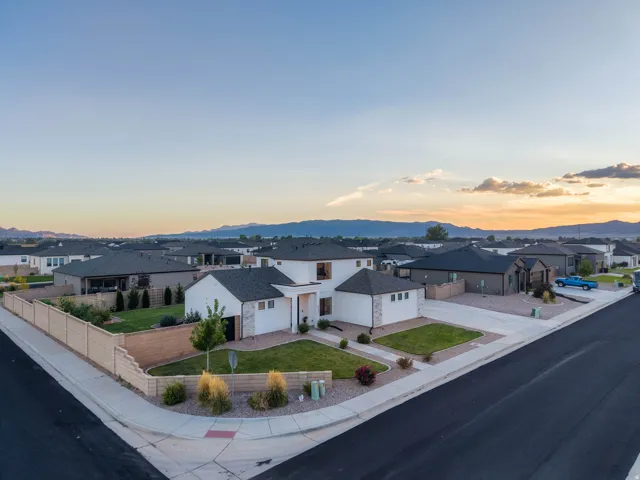 Corner lot property featuring a manicured lawn, established landscaping, and a low-maintenance perimeter fence