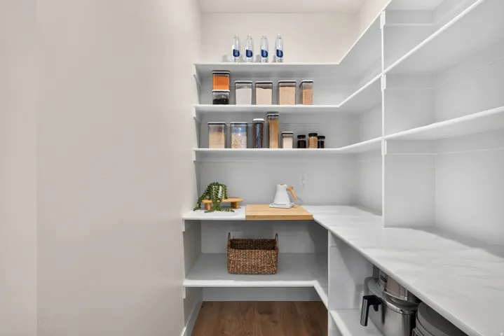 Built-in shelving, white countertops, wood-finish flooring, and light wall finishes