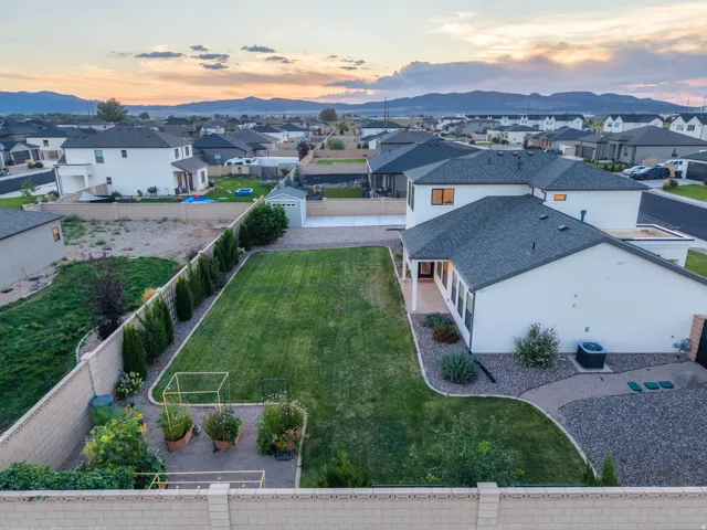 Expansive backyard featuring a manicured lawn, established landscaping, and a substantial storage shed