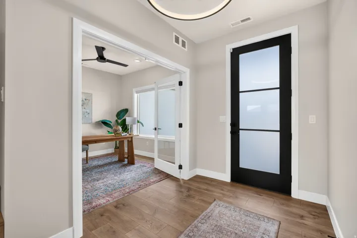 Wood-finish flooring throughout, modern black interior door with frosted glass panels, and recessed ceiling lighting