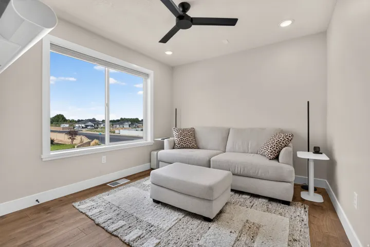 Expansive window with bright natural light, wood-finish flooring, recessed lighting, and a modern ceiling fan