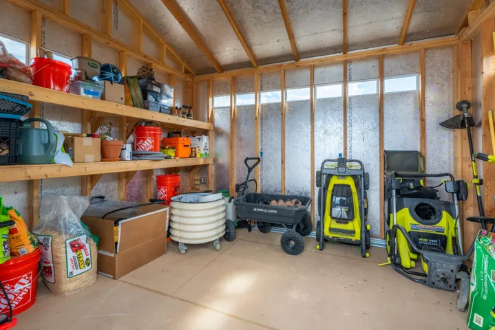 Shed interior with exposed wood framing, built-in wooden shelving, and a sloped ceiling