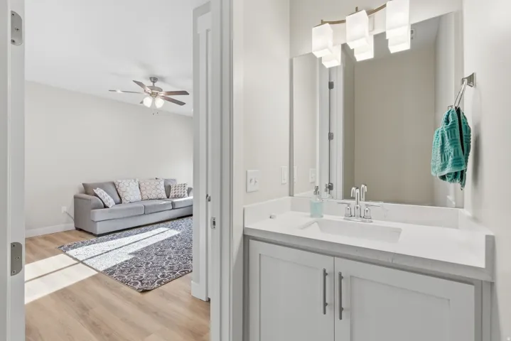 Vanity featuring white shaker-style cabinetry, a polished chrome faucet, and a large mirror