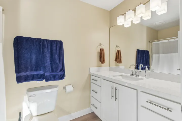 White vanity with ample storage, integrated sink, and stone-finish countertop
