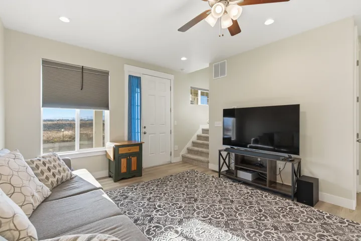 Recessed lighting, wood-finish flooring, ceiling fan with light fixture, white paneled door, and carpeted stairway