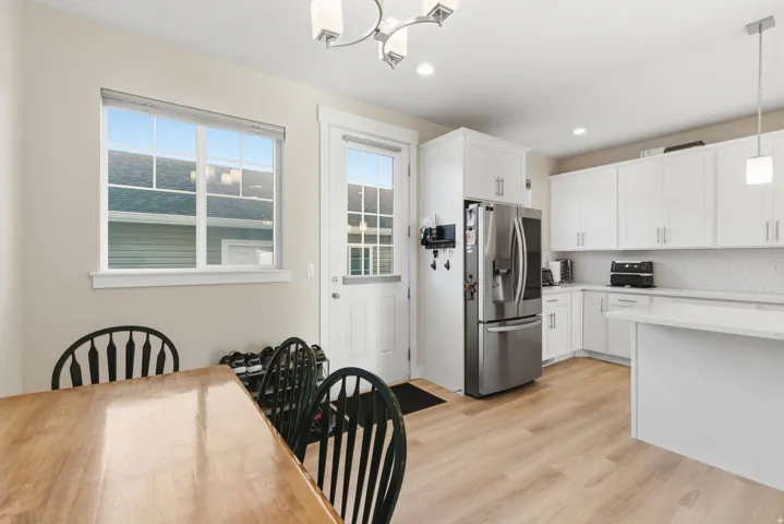 Modern kitchen featuring white cabinetry, stainless steel appliances, light wood-finish flooring, and a white subway tile backsplash