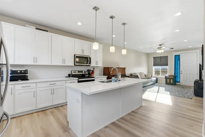 White cabinetry, recessed lighting, and a kitchen island with pendant lights