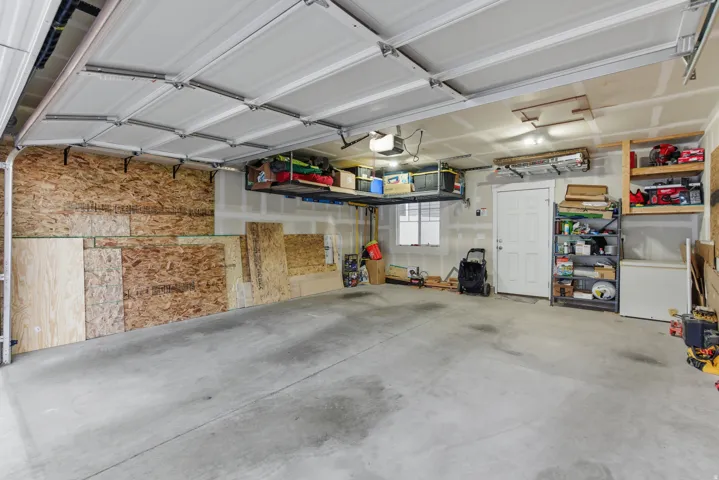 Concrete flooring, overhead storage racks, white paneled door, horizontal window, built-in shelving