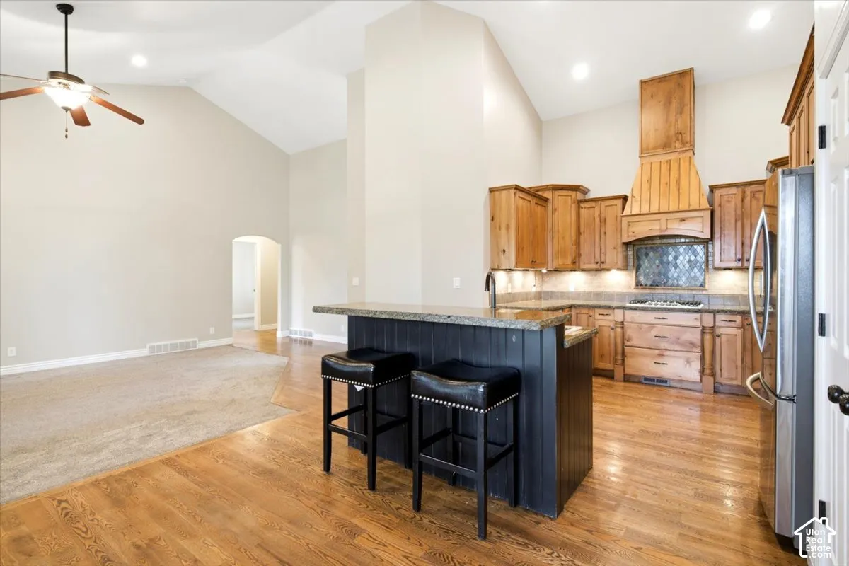 Vaulted ceilings, recessed lighting, wood-finish flooring, wood cabinetry, and a central island with bar seating