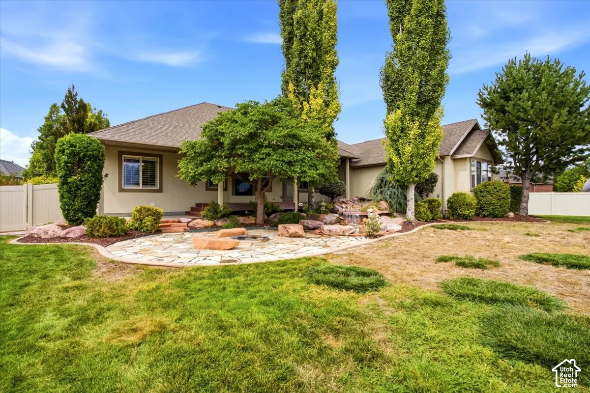 Stone patio with a rock border, water feature, and mature trees