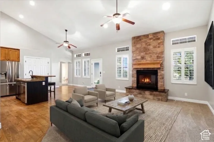 Vaulted ceilings, stone fireplace with a wood mantel, wood-finish flooring, plantation shutters, and a kitchen island with stone countertop