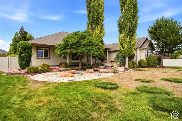 Stone patio with a rock border, water feature, and mature trees