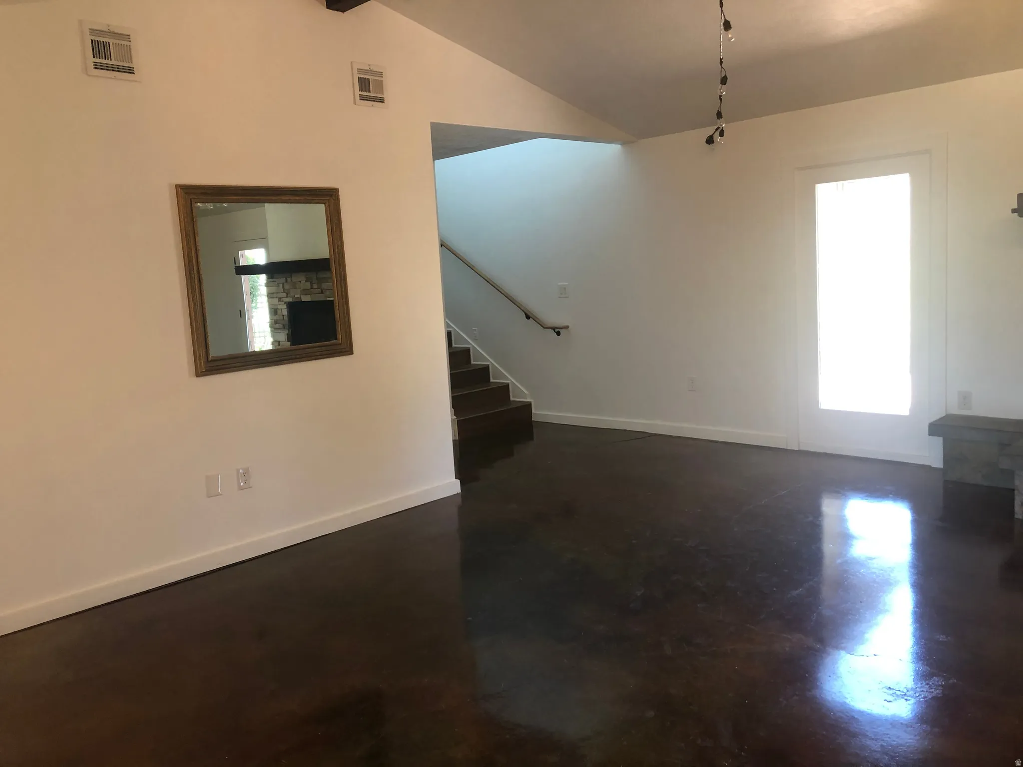Vaulted ceilings, polished concrete flooring, built-in shelving, and a prominent staircase with handrail