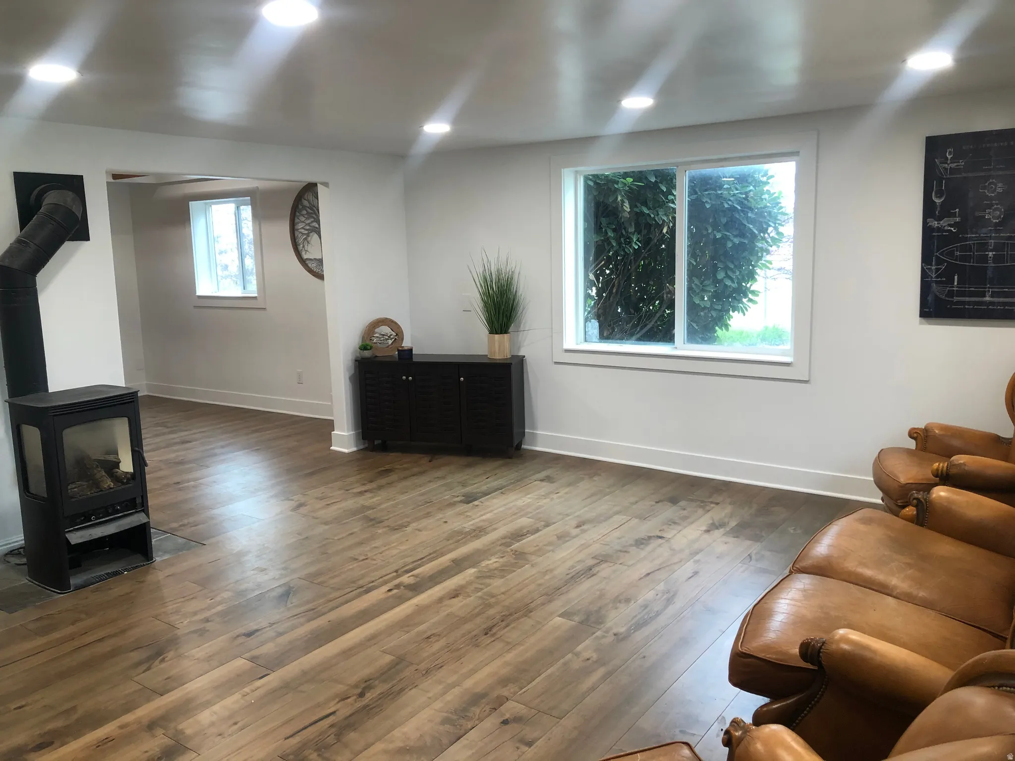 Wood-finish flooring throughout, recessed lighting, and a modern freestanding fireplace
