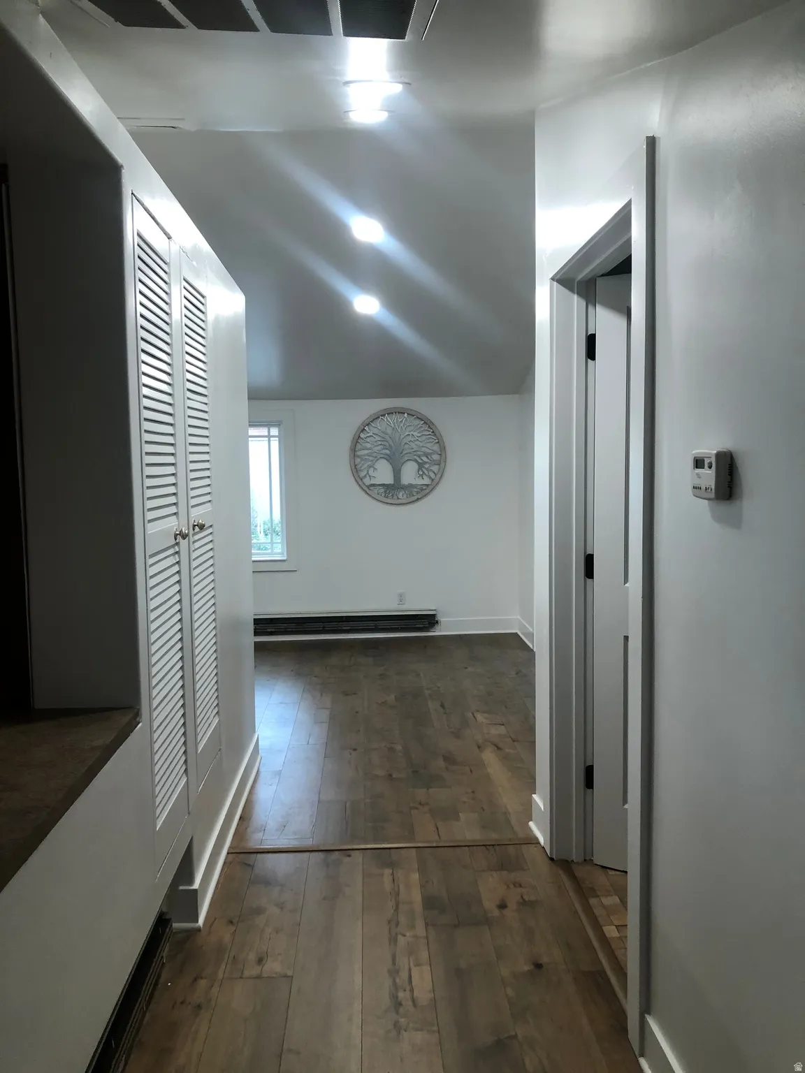 Hardwood-finish flooring, recessed lighting, white louvered cabinetry, and white painted walls