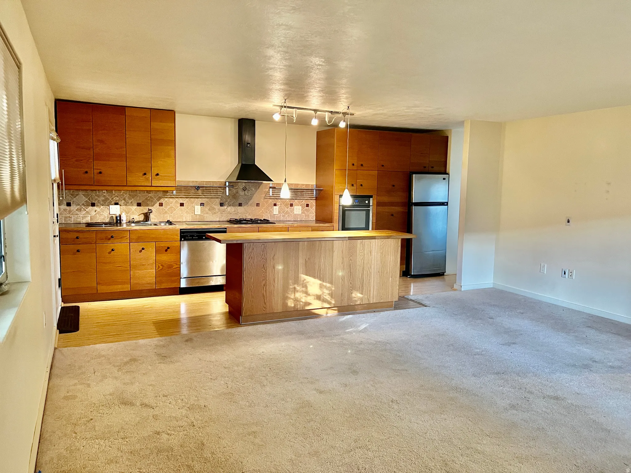 Kitchen featuring wood cabinetry, stainless steel appliances, a tiled backsplash, and an island with a built-in oven