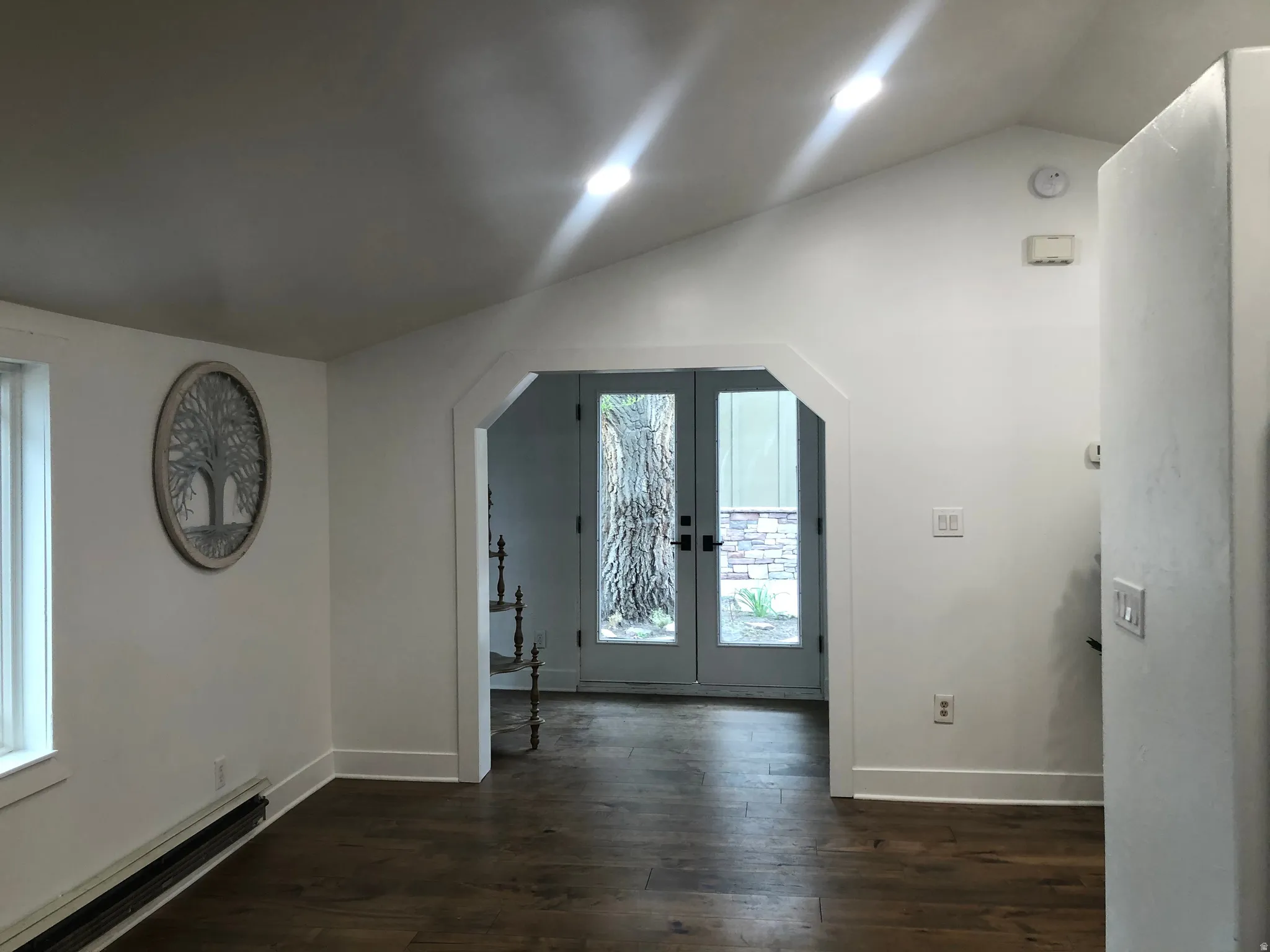 Vaulted ceiling with recessed lighting, wood-finish flooring, white walls, and French doors