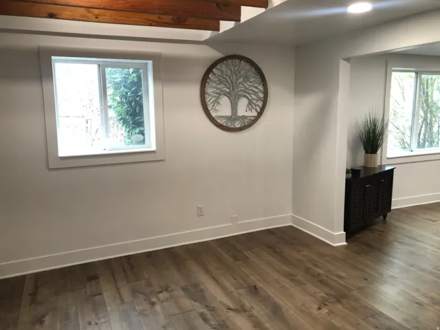 Recessed lighting, exposed wooden beams, wood-finish flooring, white trim, and white walls