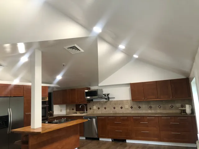 Kitchen featuring vaulted ceilings, recessed lighting, wood-finish cabinetry, stainless steel appliances, and a tile backsplash