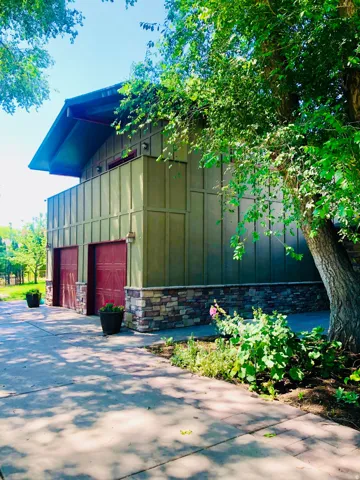 Two-story structure with board-and-batten siding, stone veneer foundation, and a concrete driveway