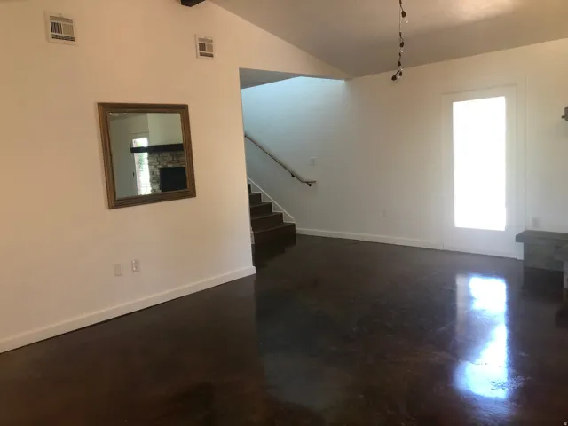 Vaulted ceilings, polished concrete flooring, built-in shelving, and a prominent staircase with handrail