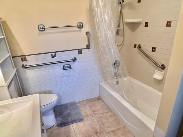 Bathroom White subway tile surround with decorative accent tiles, built-in shelving, and a white porcelain bathtub