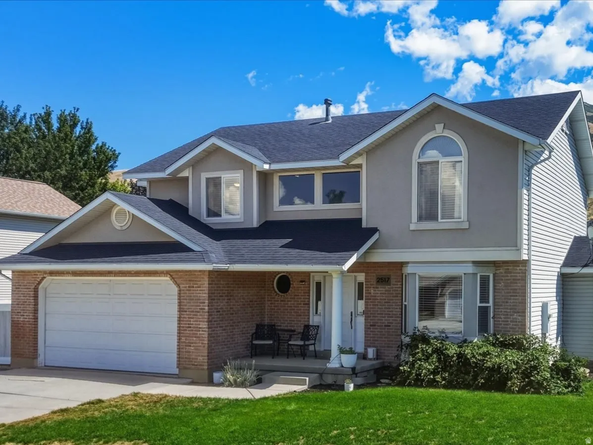 Two-story residence featuring a brick and siding exterior, an attached two-car garage, and a fenced backyard