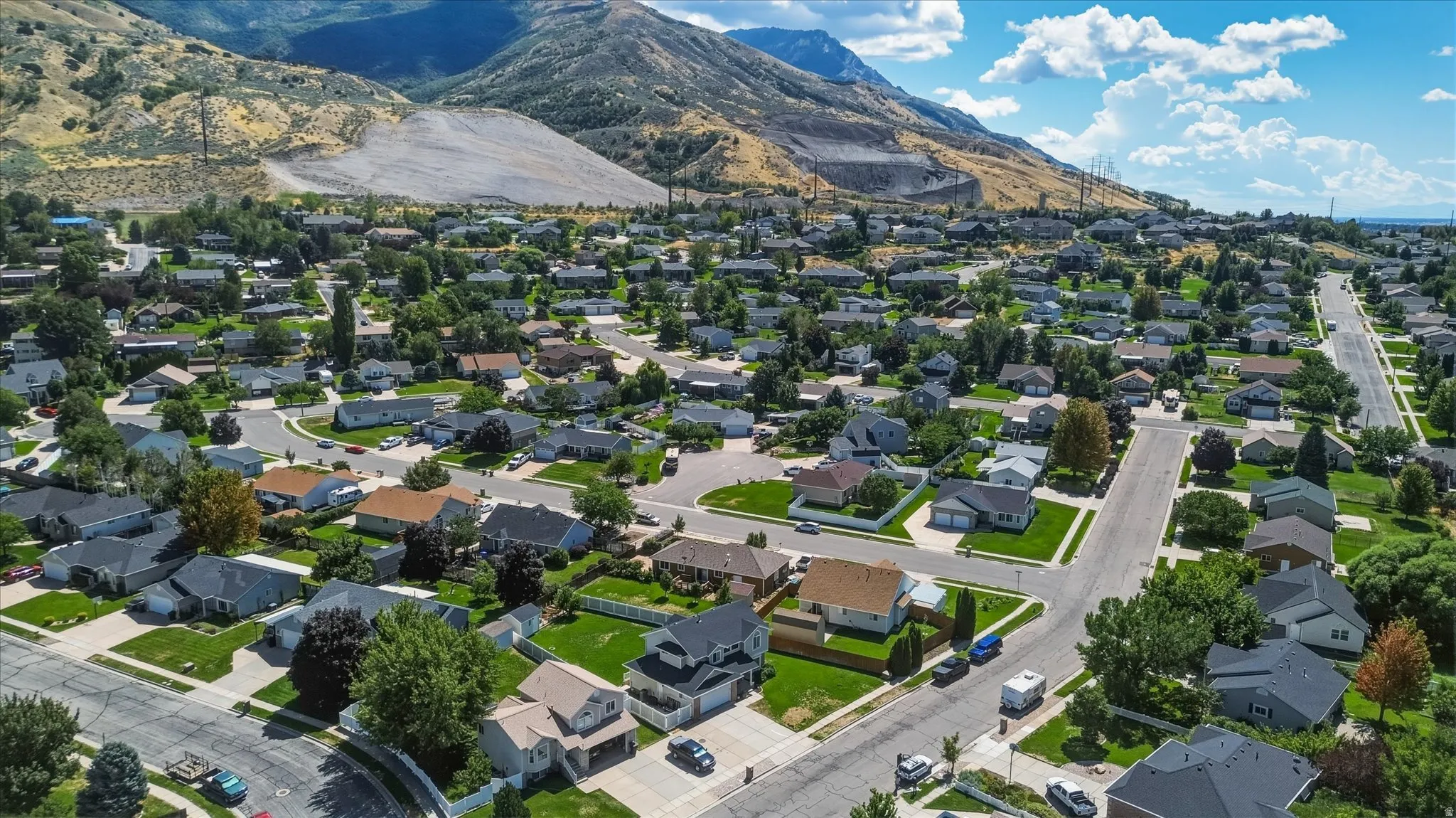 Residential neighborhood featuring paved streets, mature trees, and a mountain backdrop
